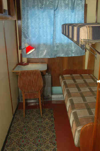 Двухместная одноярусная каюта с умывальником на главной палубе. В каюте: две односпальные кровати, столик, графин для воды, стаканы, светильник, встроенные полочки для книг, шкаф для одежды, радиоточк